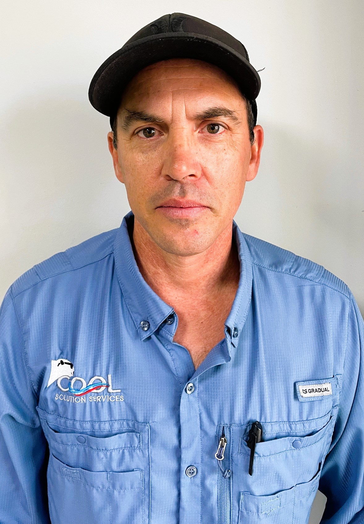 Man wearing a blue button-down shirt and a black cap